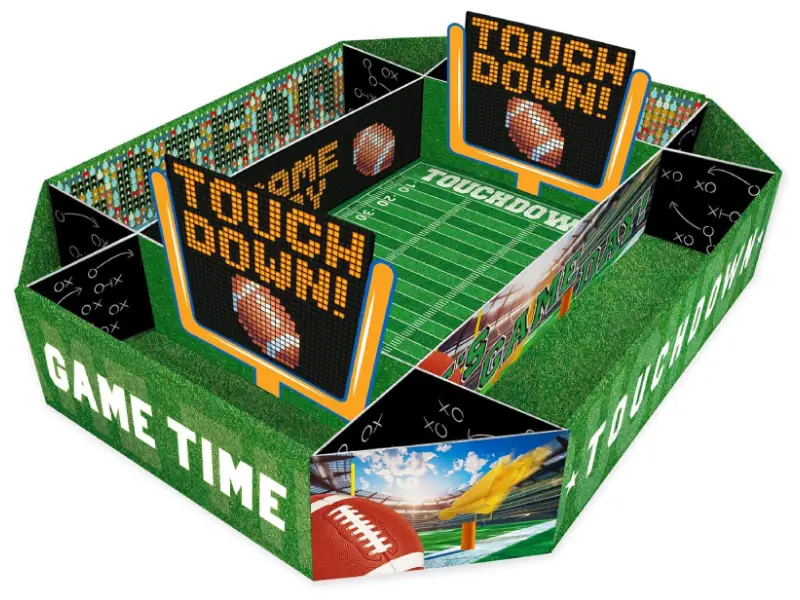 Rectangular cardboard party tray decorated as an American football stadium, with green grass-patterned sides reading “GAME TIME” and “TOUCHDOWN,” inner field graphics marked with yard lines and “TOUCHDOWN,” black play-diagram panels, and two large scoreboard-style signs showing a pixelated football and the word “TOUCHDOWN!”